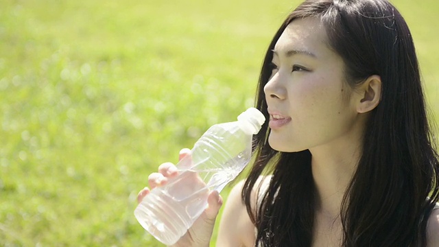 CU拍摄的女人坐在草坪上喝水/宇次，京都，日本视频素材