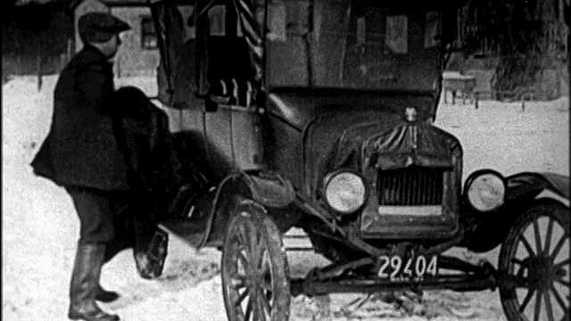 B/W 1920年代的男子脱外套+ T型车的曲柄发动机在冬季/新闻短片视频素材