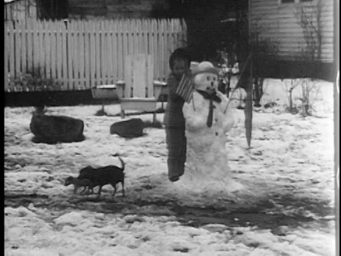 1944年，女孩站在拿着美国国旗的雪人后面/狗狗和小狗走散了/家庭电影视频素材