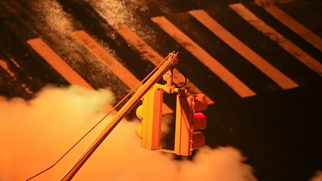 在雨夜，摄像头捕捉到交通信号和周围被从人孔流出的蒸汽包围的交通。视频素材