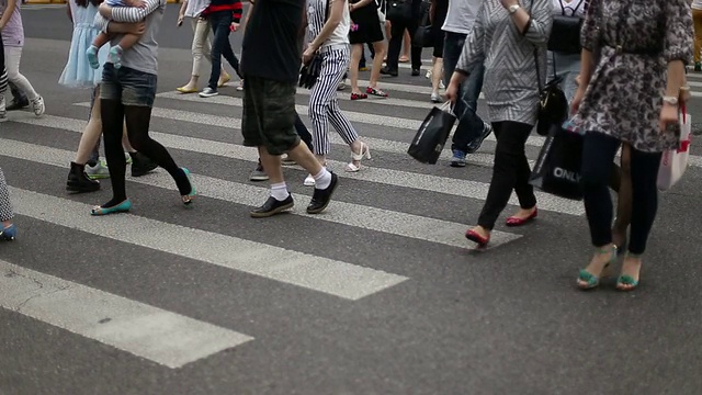 行人在城市街道斑马线上行走，实时。视频素材