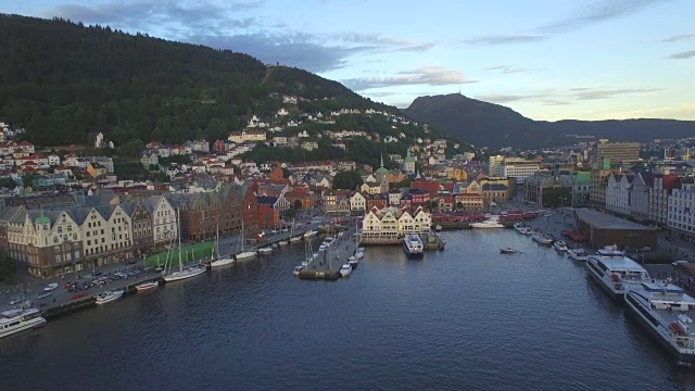 从Vågen海港俯瞰乌尔里肯山(Mount Ulriken)，位于挪威Hordaland卑尔根(Bergen)的老港区Bryggen，古老的中世纪汉萨式木制建筑上方视频素材