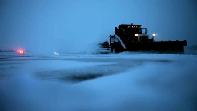 一个满是雪的跑道/飞机跑道，犁在暴风雪的夜晚刮着视频素材