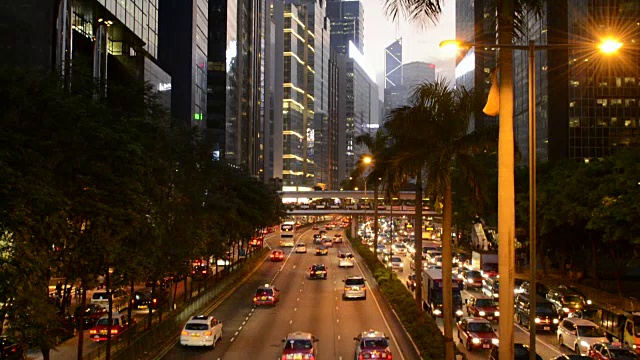 中国香港市中心告士打道的黄昏交通，在夜晚，汽车在道路上裸奔，在香港中环的摩天大楼旁边视频素材