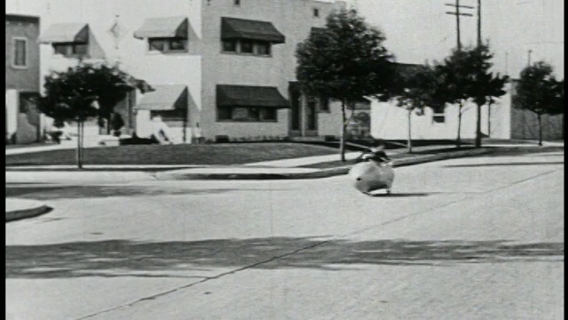 1923年B/W一名男子(Snub Pollard)开着一辆迷你车，在街道上跟随着一辆车/汽车转弯/特征视频素材