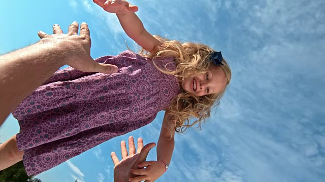 在一个阳光明媚的日子里，父亲将微笑着的女儿抛向空中视频素材画面2