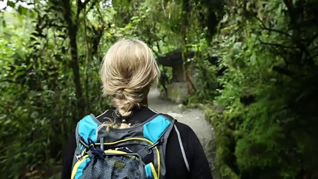 一名妇女沿着热带雨林小径行走视频素材