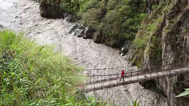 倾斜到女徒步旅行者穿过吊桥视频素材