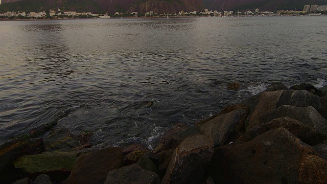 远处的小海浪拍打着岩石和休格洛夫山。视频素材