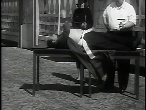 1937年宽镜头男人躺在桌子上，嘴里塞着管子/男人+女人看着视频素材