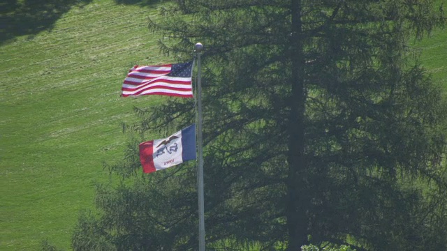 美国国旗和爱荷华州国旗挥舞，而人们走在背景/艾姆斯，爱荷华州，美国视频素材