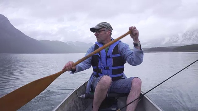 一名男子划着船，将钓鱼线荡入山中湖中视频素材