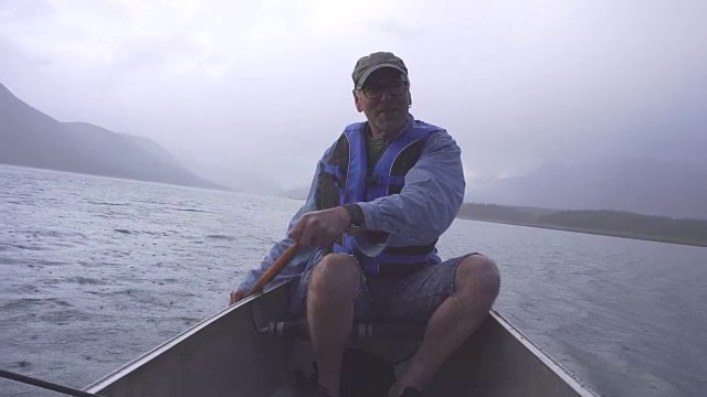 人在山湖中划着船，在暴风雨中视频素材