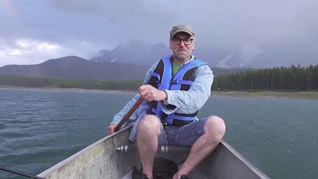 人在山湖中划着船，在暴风雨中视频素材