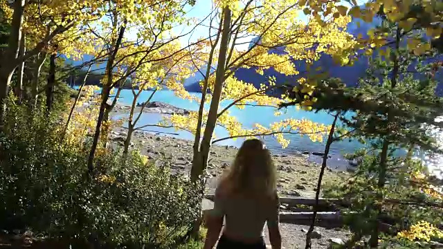 年轻女子走到湖边欣赏山景视频素材