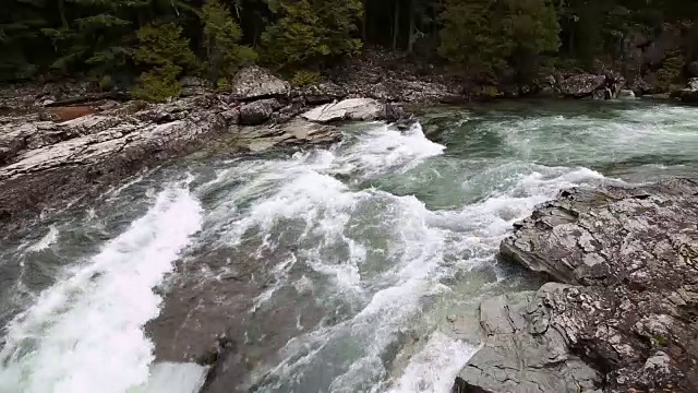 美丽的碧水急流在河流中穿过青苔覆盖的岩石。视频素材