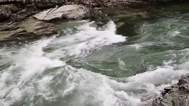 美丽的碧水急流在河流中穿过青苔覆盖的岩石。视频素材