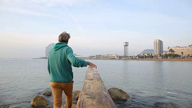 人跟在海上的木栏杆后面，后面是城市建筑视频素材