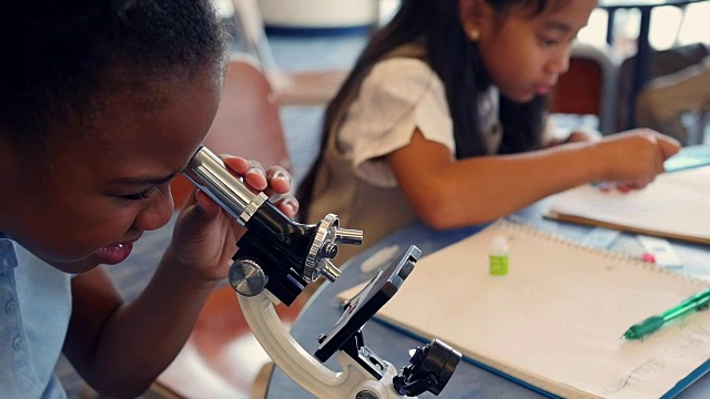 可爱的非裔美国STEM学校学生用显微镜检查东西视频下载