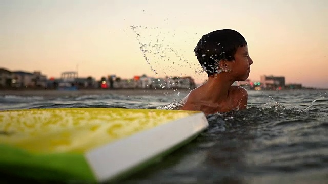 小男孩在冲浪板上冲浪时摔倒了视频素材