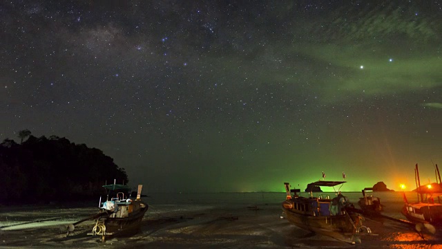 长尾船在夜晚停泊在海滩上，头顶有星星和银河星座视频素材