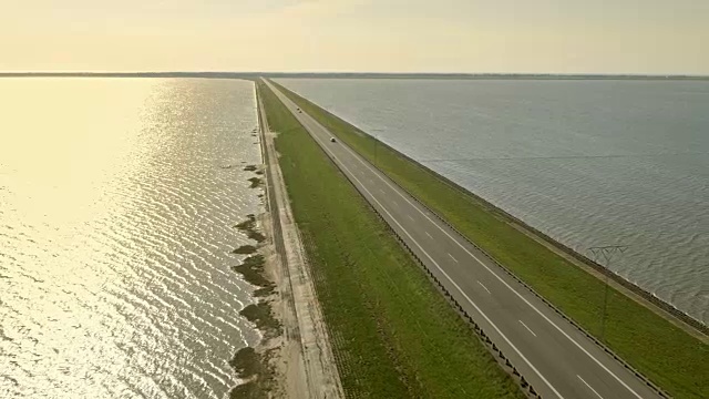 日落时横跨大海的水坝上的空中公路视频素材画面1