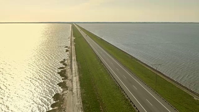 日落时横跨大海的水坝上的空中公路视频素材画面2