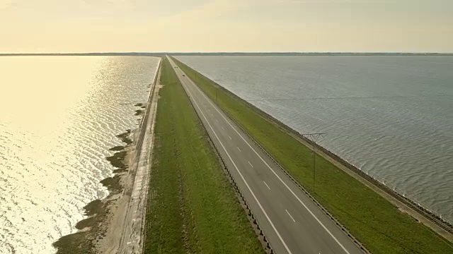 日落时横跨大海的水坝上的空中公路视频素材画面3