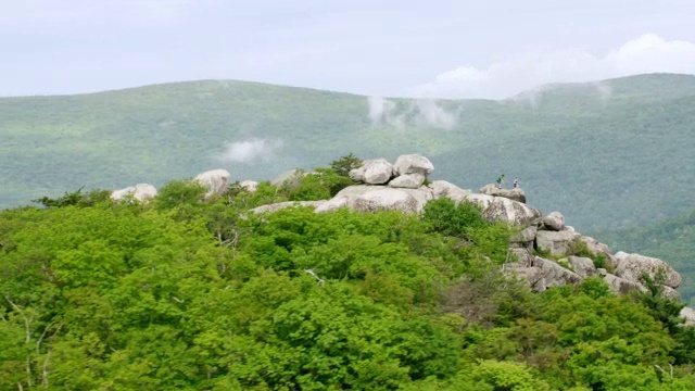 两个人站在雪兰多厄国家公园的蓝岭山顶，背景是森林和云/雪兰多厄山谷，美国弗吉尼亚州视频素材