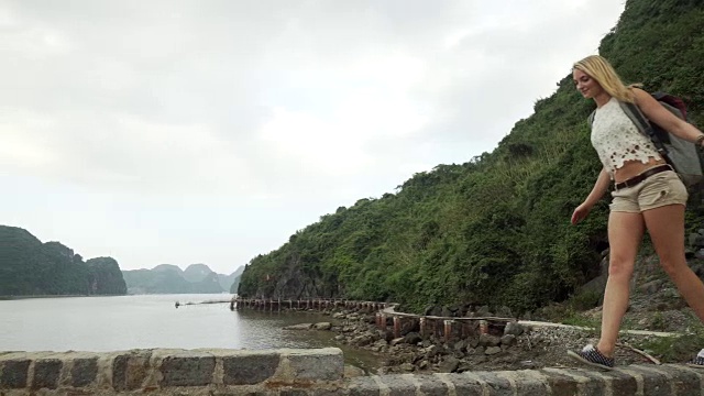 女孩沿着海湾走在砖墙上视频素材