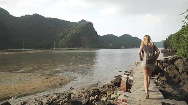 女孩沿着越南山下的海湾走在码头上视频素材