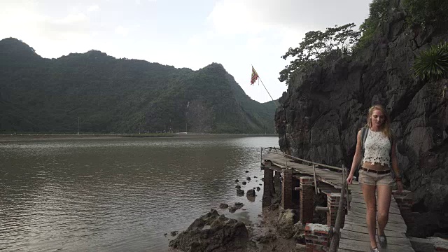 女孩沿着越南山下的海湾走在码头上视频素材