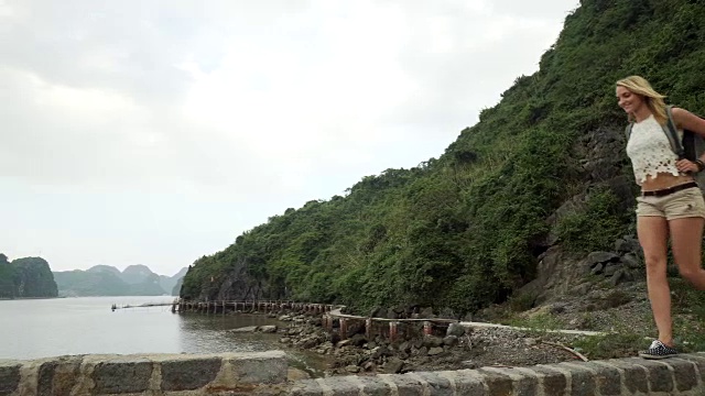 女孩沿着海湾走在砖墙上视频素材