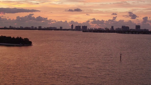 在迈阿密的夕阳下，空中漂浮在闪闪发光的粉红色和金色的海洋上视频素材