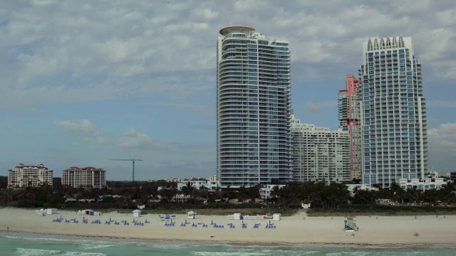 空中拍摄迈阿密海滩，沙滩上排列着躺椅和白色旅馆视频素材