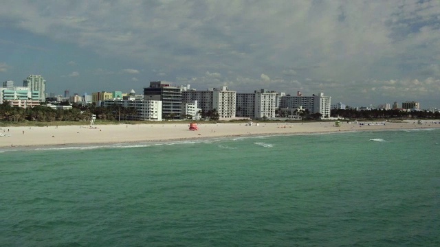 从空中拍向迈阿密的海滩，那里有一排排的躺椅和白色的旅馆视频素材