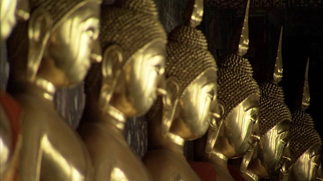 把焦点拉到一排寺庙里的金佛雕像上。视频素材画面4