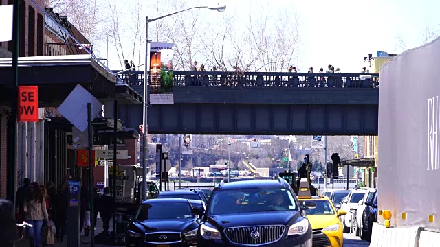 人们走在高线公园(The High Line Park)上，它位于曼哈顿肉类加工区(Meatpacking District)拥挤的街道上方。视频素材