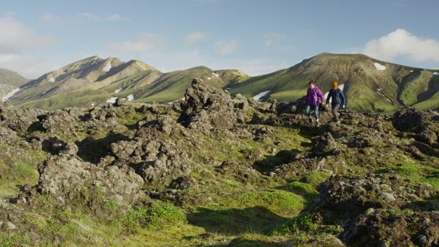 宽摇摄的妇女徒步旅行在绿色的山脉/冰岛视频素材