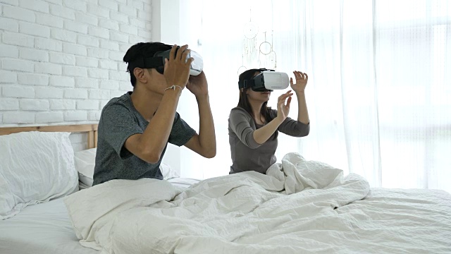 漂亮的年轻夫妇戴着虚拟现实眼镜在家视频素材画面4
