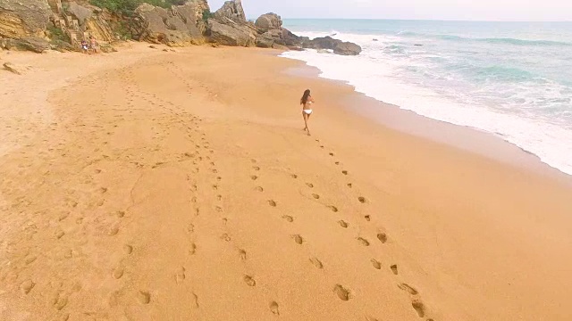 航拍的一个女人独自在一个惊人的和未被破坏的海滩在西班牙海岸视频素材