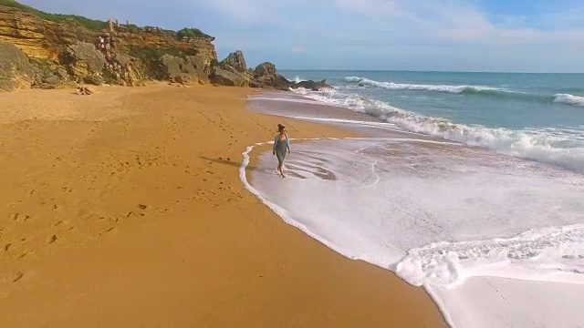 航拍的一个女人独自在一个惊人的和未被破坏的海滩在西班牙海岸视频素材