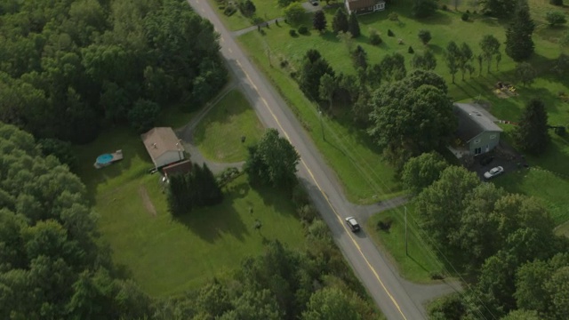 汽车在乡村道路上行驶的天线。林中的树林中的树农田，田野和草地。视频素材