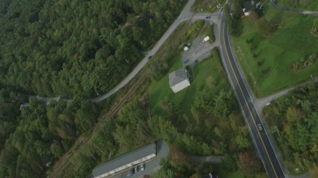 汽车在乡村或农村地区道路上行驶的天线。房屋。林中的树林中的树湖。视频素材