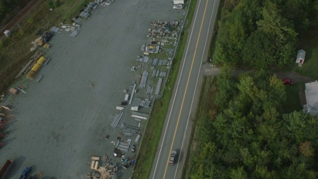 汽车在乡村或农村地区道路上行驶的天线。房屋。林中的树林中的树视频素材