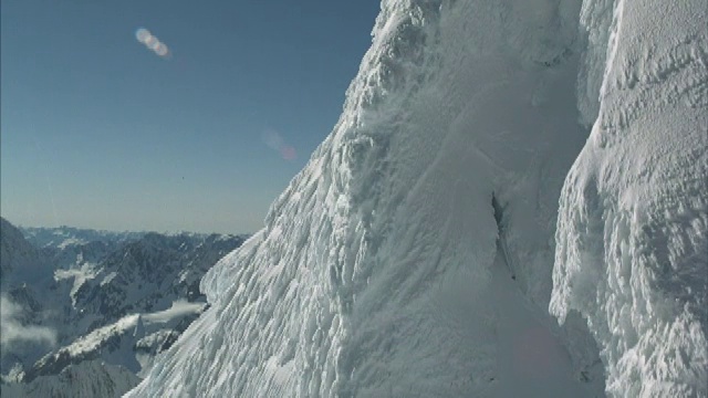 空中飞过云雾，飞向崎岖的雪山山顶。视频素材