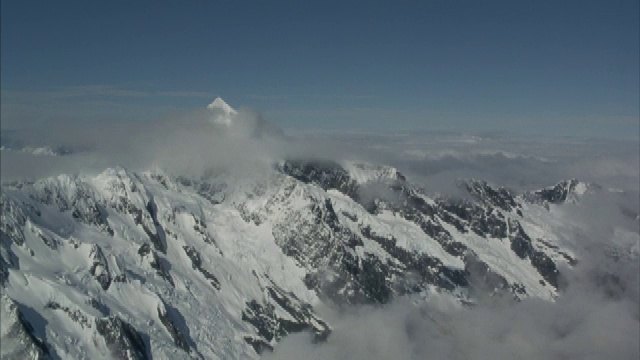 空中飞过云层，飞向一座部分被遮蔽的岩石覆盖的山峰。视频素材