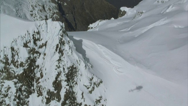 空中盘旋和下山坡崎岖的积雪覆盖的山峰。视频素材