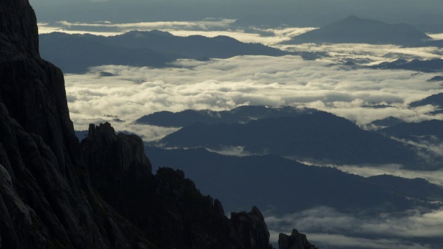 在婆罗洲基纳巴卢山岩石峰下的森林上空的延时云视频素材