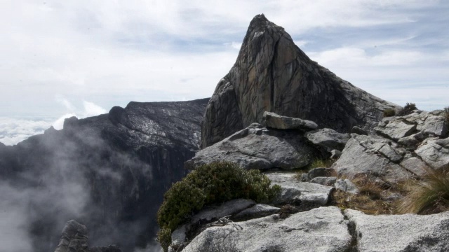 在婆罗洲基纳巴卢山的岩石山峰上，时间推移的云翻腾视频素材